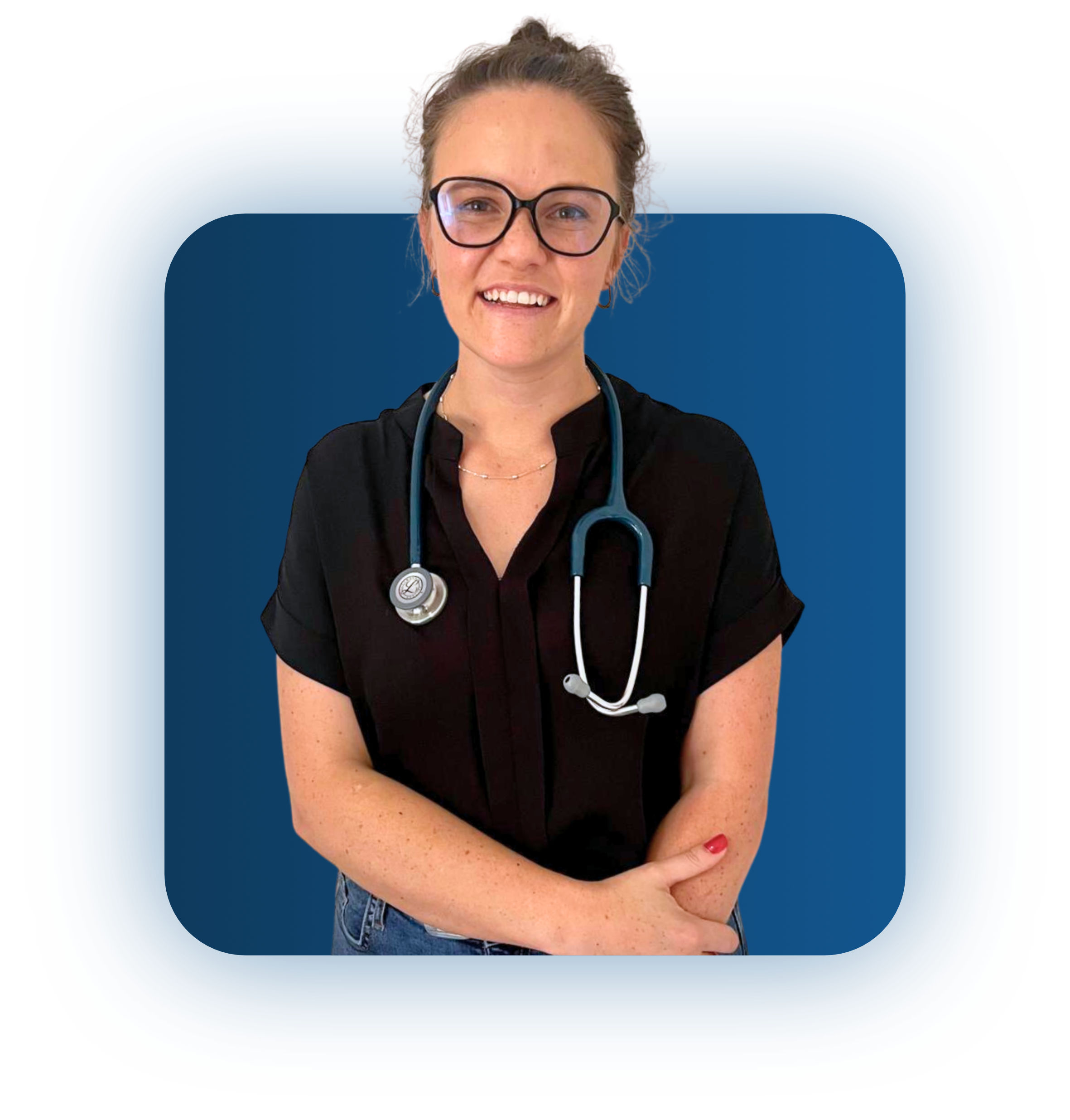 Smiling woman with glasses and stethoscope around her neck wearing a black shirt and blue jeans against a blue background.